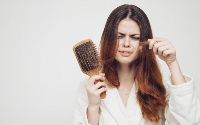 Una mujer retira del cepillo pelos de su melena.