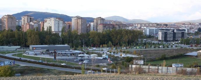 Vista del terreno donde se va a construir el centro comercial, junto a la gasolinera. Al fondo, viviendas de Azpilagaña y Milagrosa.