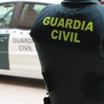 Un agente de la Guardia Civil, de espaldas, junto a un veh&iacute;culo oficial