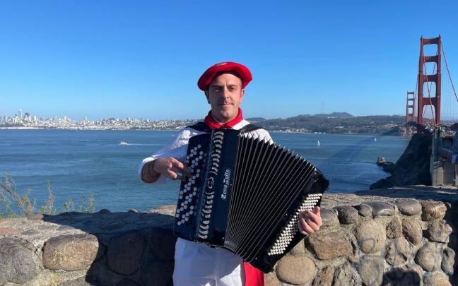 I&ntilde;aki Reta, con uno de sus acordeones y vestido de pamplonica, ante el Golden Gate, el puente de San Francisco.