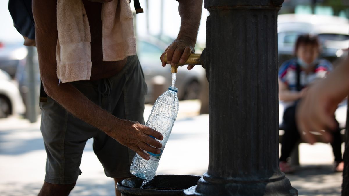 Un hombre rellena una botella de agua en una fuente en plena ola de calor.