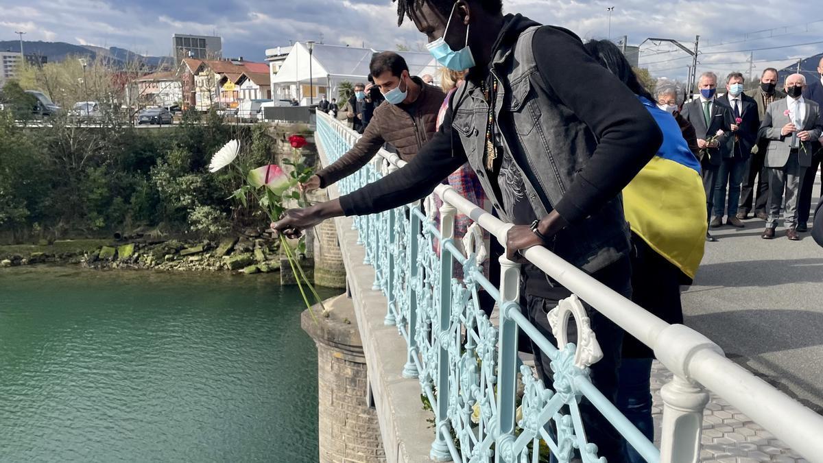 Un migrante realiza una ofrenda floral, en el río Bidasoa, desde el Puente de Santiago de Irun, tras la muerte de varias personas intentando pasar a Francia.