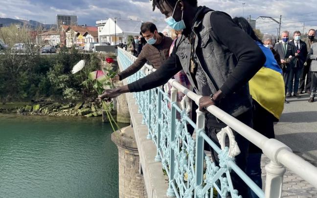 Un migrante realiza una ofrenda floral, en el río Bidasoa, desde el Puente de Santiago de Irun, tras la muerte de varias personas intentando pasar a Francia.