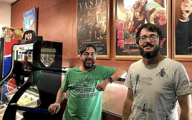 Edorta Mart&iacute;nez y Xabier Amenabarro junto a la cartelera y el estand de dulces y palomitas.