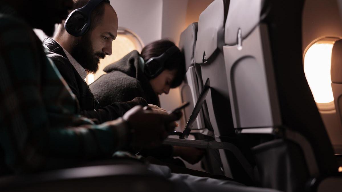Varias personas con dispositivos electrónicos en un avión.