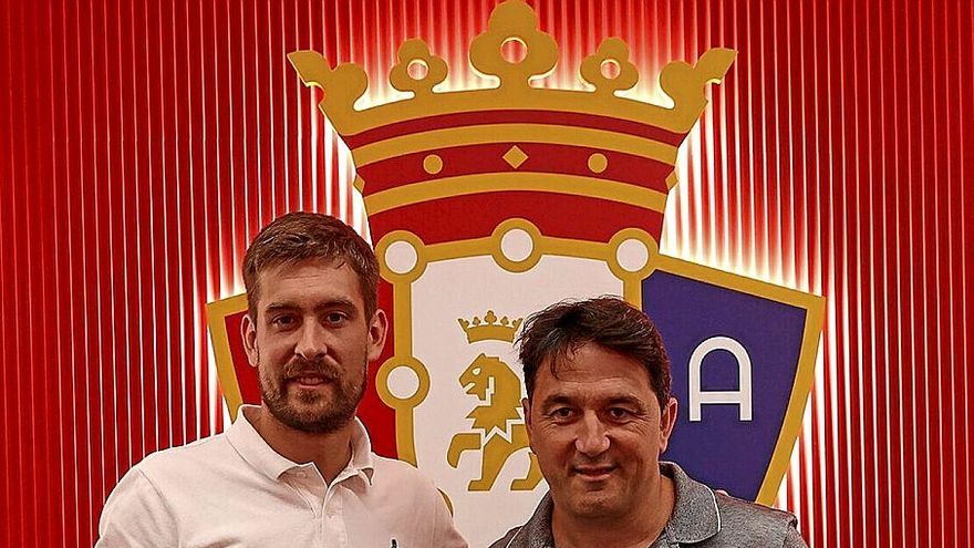 Aitor Fernández posa con su nueva camiseta y con Braulio Vázquez delante de un escudo de Osasuna.