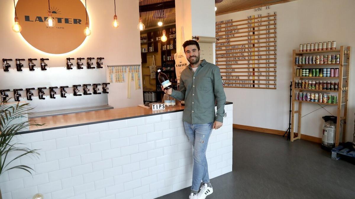 Diego Polo posa en Lauter Craft Beer, con los 18 grifos de cerveza a granel y la pizarra donde están escritas las variedades de cervezas que ofrece.