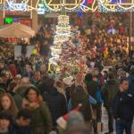 Cientos de personas pasean por una calle muy iluminada de Navidad, haciendo sus compras.