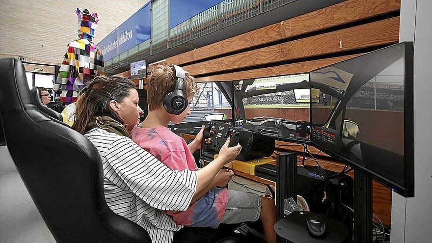Una mujer y un niño prueban un simulador de conducción.