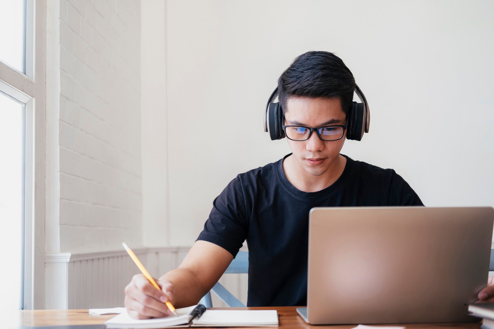 Un joven estudia en casa utilizando un ordenador portátil.