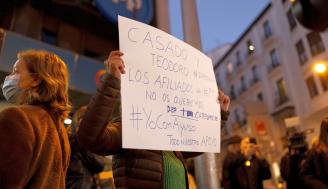 Una afiliada sostiene un cartel pidiendo la dimisión de Casado.