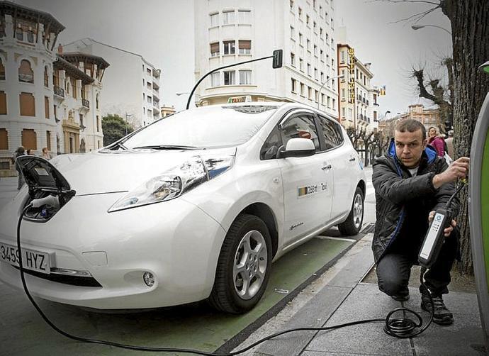 Un conductor carga un taxi eléctrico.