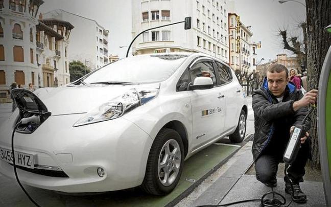 Un conductor carga un taxi eléctrico.