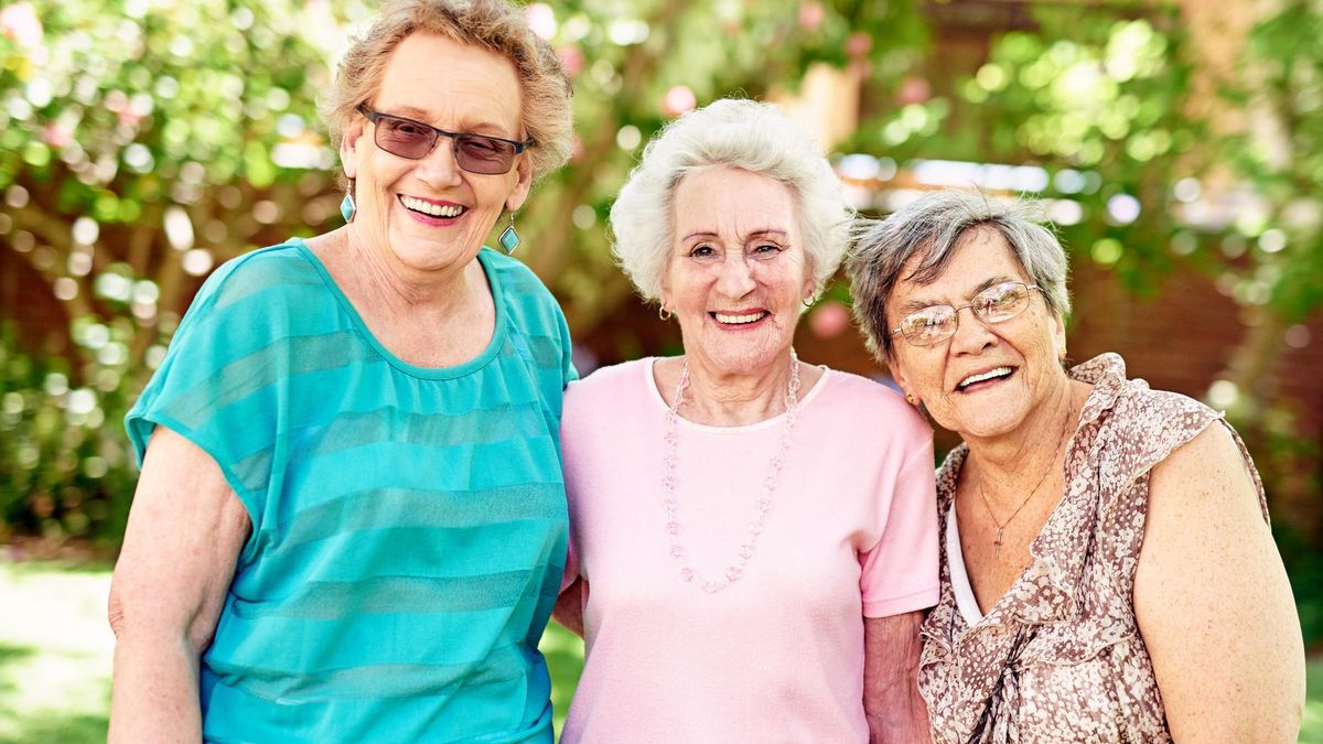 Tres mujeres de avanzada edad sonríen mientras posan para una foto.