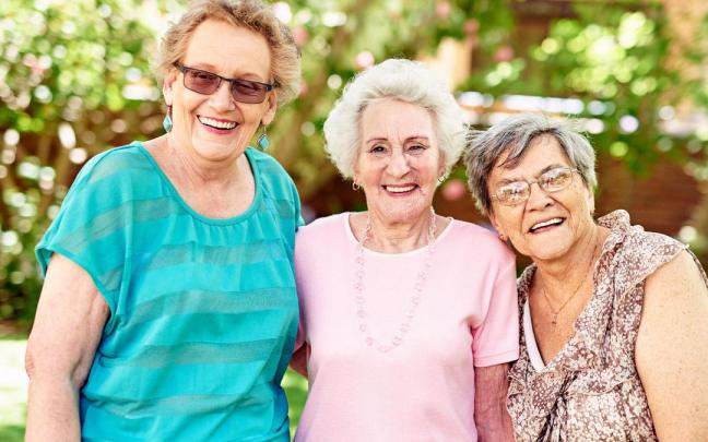Tres mujeres de avanzada edad sonríen mientras posan para una foto. Tres mujeres de avanzada edad sonríen mientras posan para una foto.