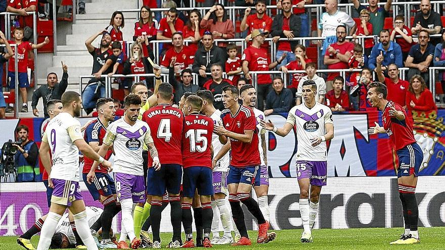 Guillermo Cuadra Hernández recibe las protestas de los jugadores de Osasuna mientras enseña la amarilla a un sorprendido y quejoso Lucas Torró.