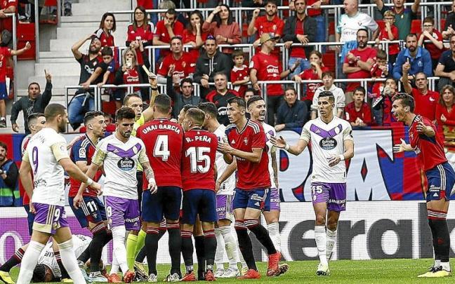 Guillermo Cuadra Hernández recibe las protestas de los jugadores de Osasuna mientras enseña la amarilla a un sorprendido y quejoso Lucas Torró.