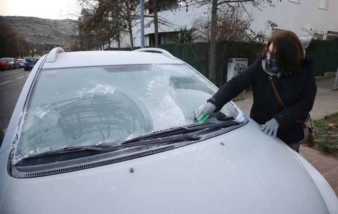 Quitando el hielo de la luna del coche tras una noche bajo cero