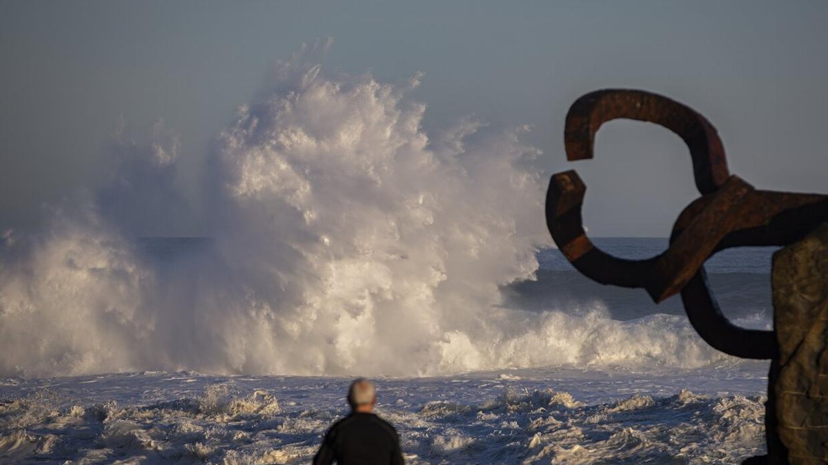 Un hombre observa el oleaje a primera hora de este lunes en Donostia junto a la escultura El Peine del Viento, de Eduardo Chillida.