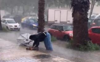 Fidel, con el paraguas doblado y roto, tropezando con la acera entre la granizada. Fidel, con el paraguas doblado y roto, tropezando con la acera entre la granizada.