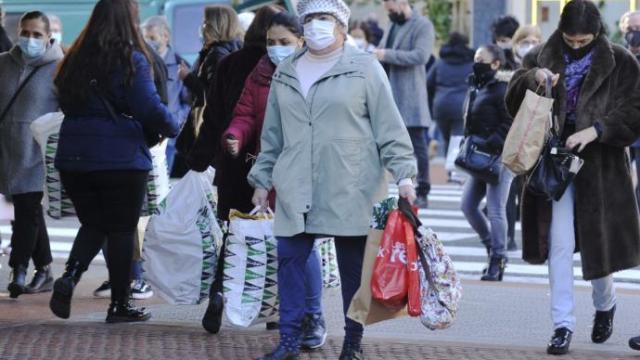 Una persona pasea por la Gran Vía cargada de bolsas.