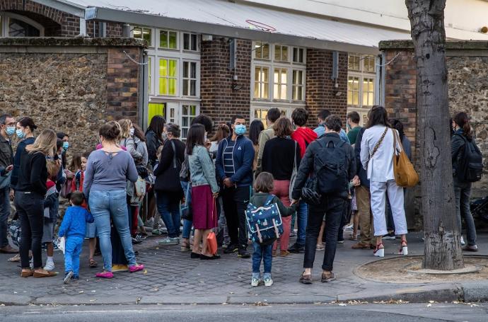 Alumnos esperan a la entrada de una escuela en París.