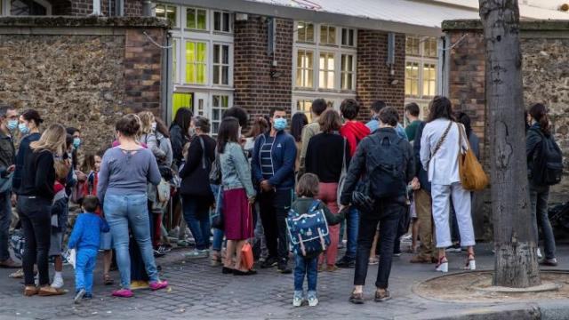 Alumnos esperan a la entrada de una escuela en París.
