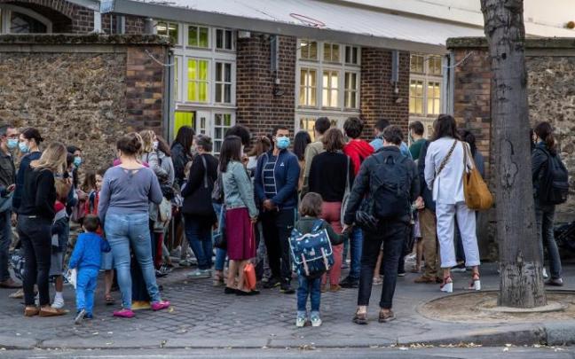 Alumnos esperan a la entrada de una escuela en París.