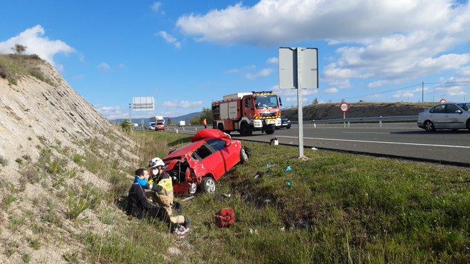 Un bombero ayudando al herido tras salirse su coche de la calzada