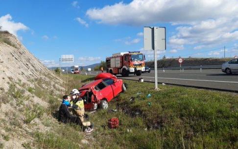Un bombero ayudando al herido tras salirse su coche de la calzada