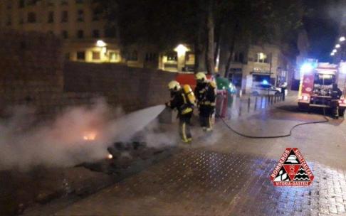 Bomberos apagando el contenedor incendiado en la calle Fueros.
