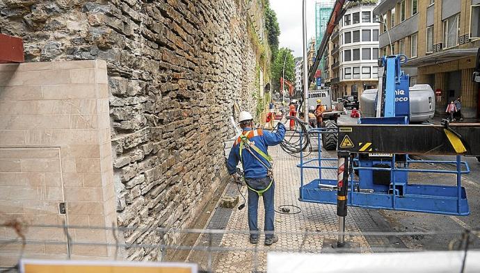 Trabajadores junto al muro de la calle San Bartolomé, donde se colocarán placas para tapar los nuevos anclajes que refuerzan el muro.