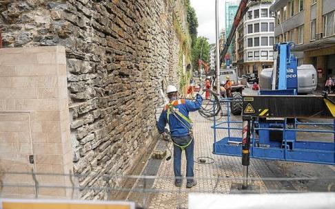 Trabajadores junto al muro de la calle San Bartolomé, donde se colocarán placas para tapar los nuevos anclajes que refuerzan el muro. Trabajadores junto al muro de la calle San Bartolomé, donde se colocarán placas para tapar los nuevos anclajes que refuerzan el muro.