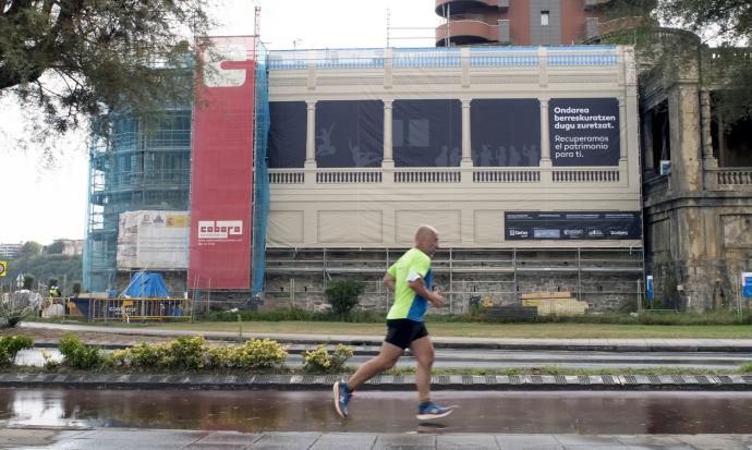 Un hombre hace deporte con las galerías de Punta Begoña al fondo, que ya lucen las lonas que recrean la futura imagen.