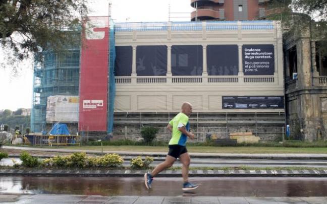 Un hombre hace deporte con las galerías de Punta Begoña al fondo, que ya lucen las lonas que recrean la futura imagen.
