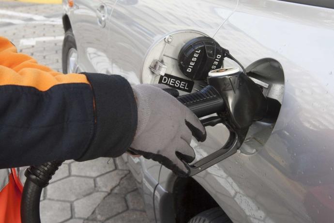 Trabajador llenando un coche de gasóleo en una gasolinera.