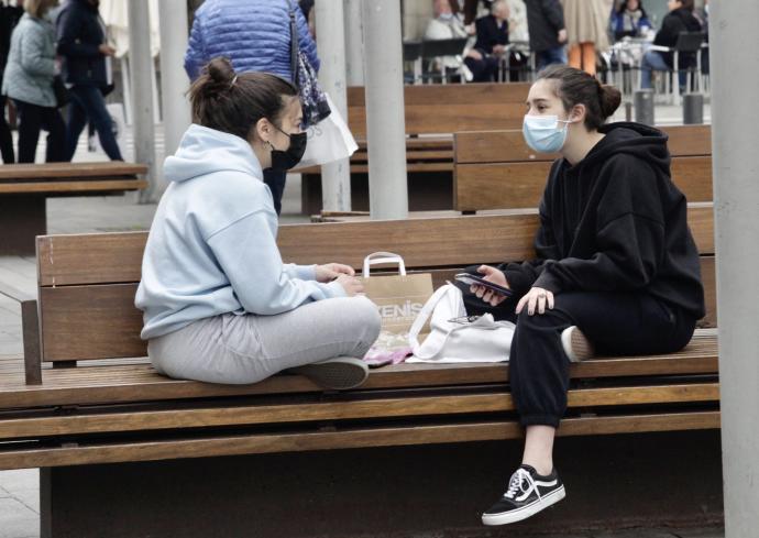 Dos jóvenes charlan en un banco en el centro de Vitoria.
