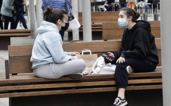 Dos jóvenes charlan en un banco en el centro de Vitoria.