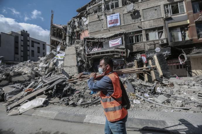 Un hombre limpia los escombros provocados por los bombardeos israelíes en Gaza en mayo