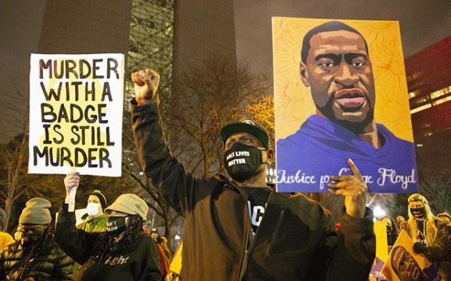 Un hombre sujeta un retrato de George Floyd durante una protesta.