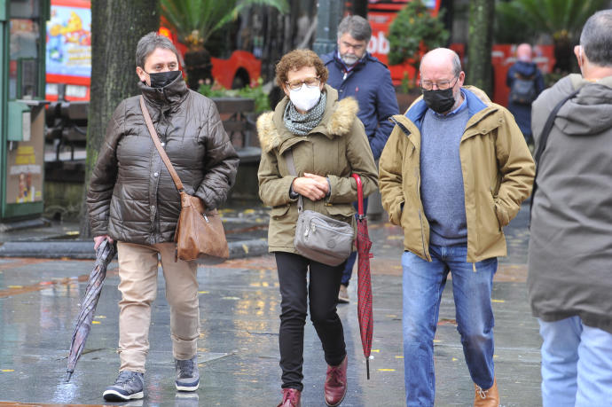 Varias personas pasean protegidas con mascarilla por la pandemia del coronavirus