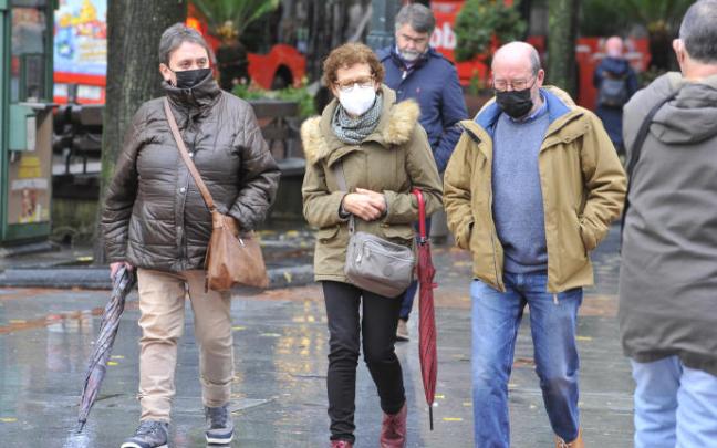 Varias personas pasean protegidas con mascarilla por la pandemia del coronavirus