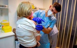 Un sanitario administra una vacuna de la gripe a una mujer