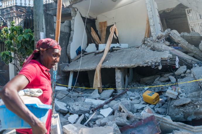 Una mujer pasa por delante de una casa destruida por el terremoto.