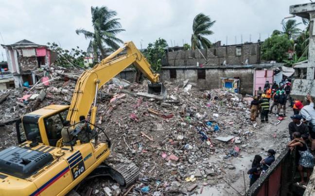Una excavadora trabaja entre los escombros de un edificio destruido. Una excavadora trabaja entre los escombros de un edificio destruido.