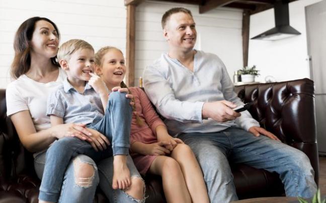 Una familia sentada frente a la pantalla de la televisión