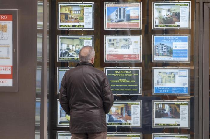 Un hombre mira ofertas de viviendas en el escaparate de una inmobiliaria.
