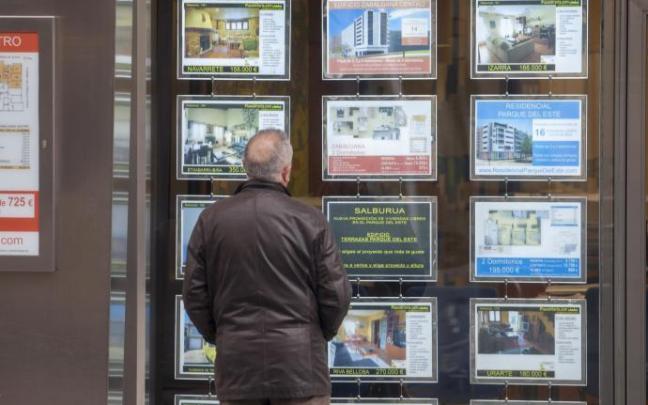 Un hombre mira ofertas de viviendas en el escaparate de una inmobiliaria.