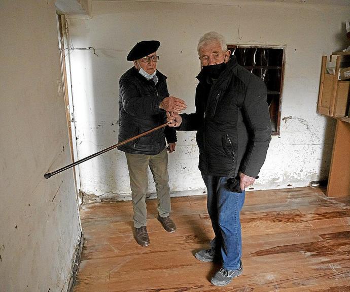 Javier Zoroquiain Villanueva (izda.) y Luciano Garde Bidaurreta (dcha.), vecinos de Burlada, señalan la altura que alcanzó el agua en la casa del primero a causa de las inundaciones.