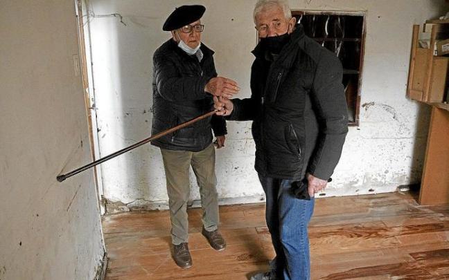 Javier Zoroquiain Villanueva (izda.) y Luciano Garde Bidaurreta (dcha.), vecinos de Burlada, señalan la altura que alcanzó el agua en la casa del primero a causa de las inundaciones.